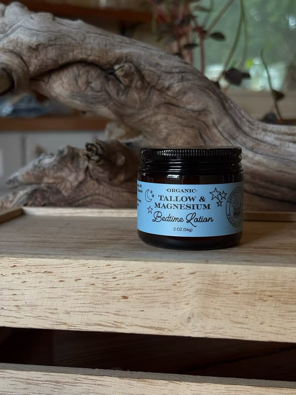 A jar of 'Bedtime Calm' Organic Tallow & Magnesium supplement by The Driftwood Shop, placed on a rustic wooden shelf with a piece of driftwood in the background.